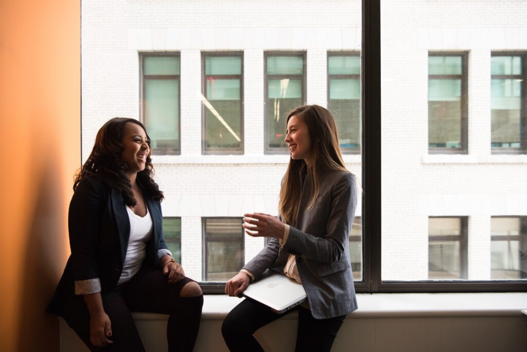 Two students sitting in front of a window.